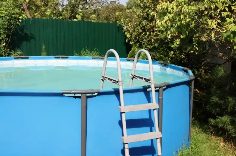 Overjordisk pool ved grønt hegn, klar til fjernelse.