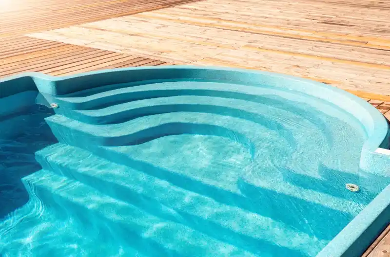 Nybygget glasfiberpool med lyse trægulve omkring, fokus på moderne pooldesign og æstetik.