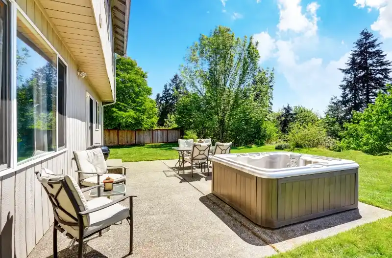 Spabad i baghaven omgivet af frodige grønne planter, illustrerer luksus og afslapning.